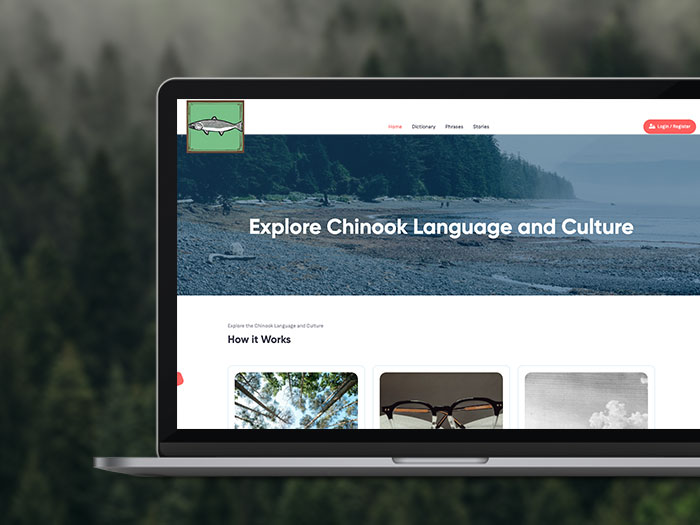 A laptop screen displays a website with the title "Explore Chinook Language and Culture" against a backdrop of a rocky beach and forest. The website features sections titled "How it Works" with various images. The laptop is set against an out-of-focus forest background.